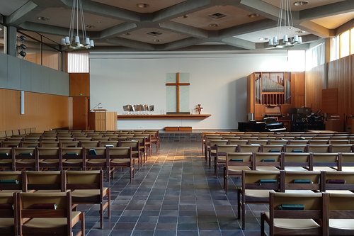 Kotkan seurakuntakeskuksen sali, penkkirivejä ja edessä puhujakoroke, risti ja urut.