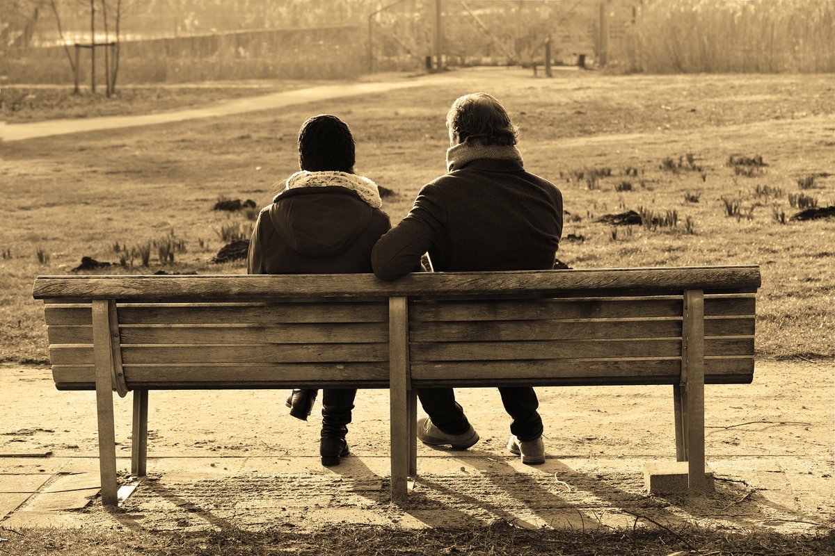 Pariskunta istuu puistonpenkillä vierekkäin. 