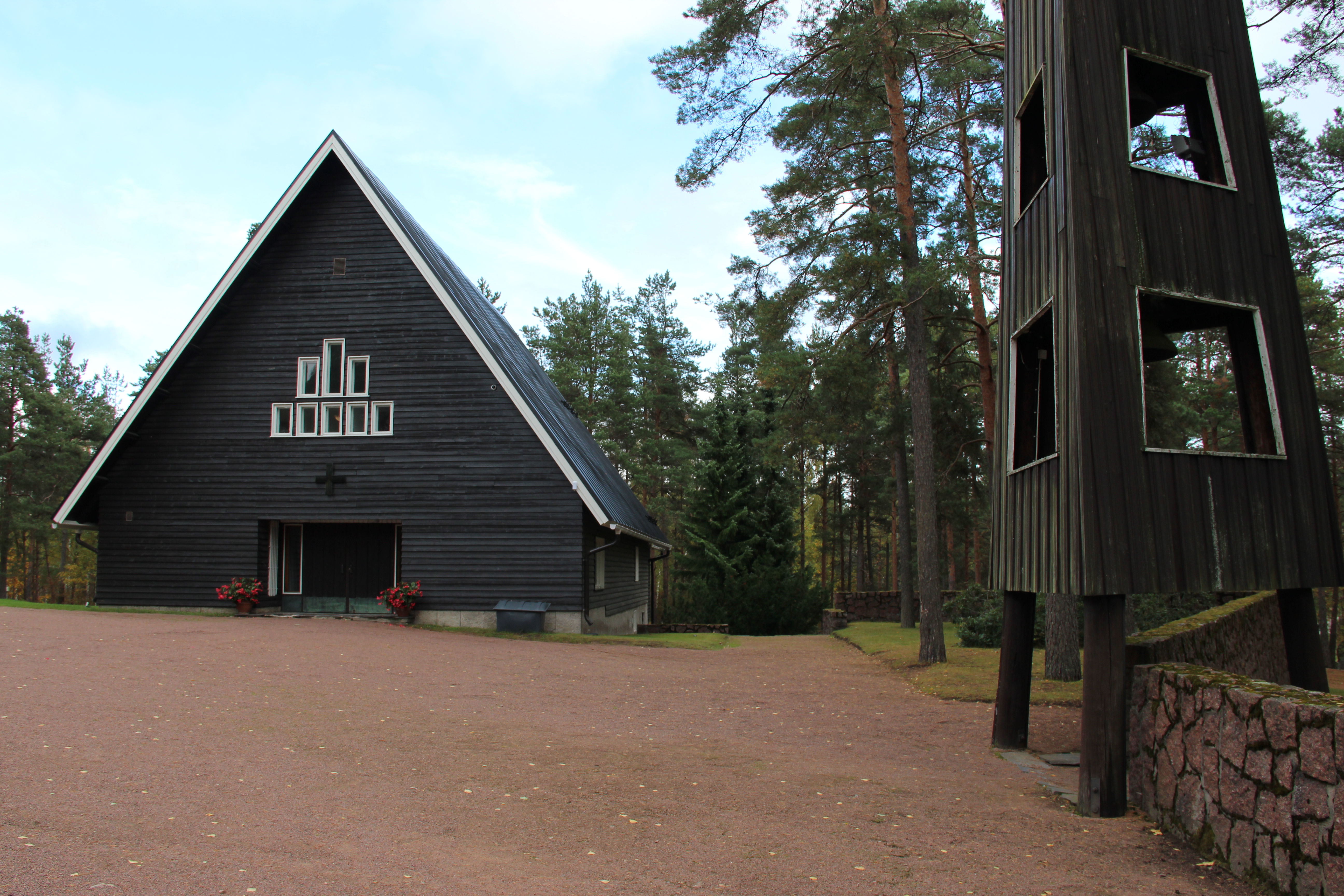 Kappeli ulkoa, korkea harjakatto, tummat puuseinät.