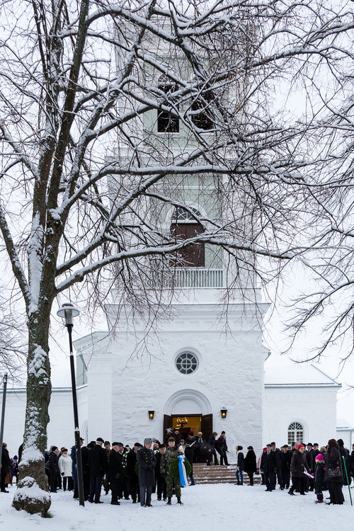 Kuvassa Kymin kirkon edestä lähtee seppelepartio sankarihautausmaalle.