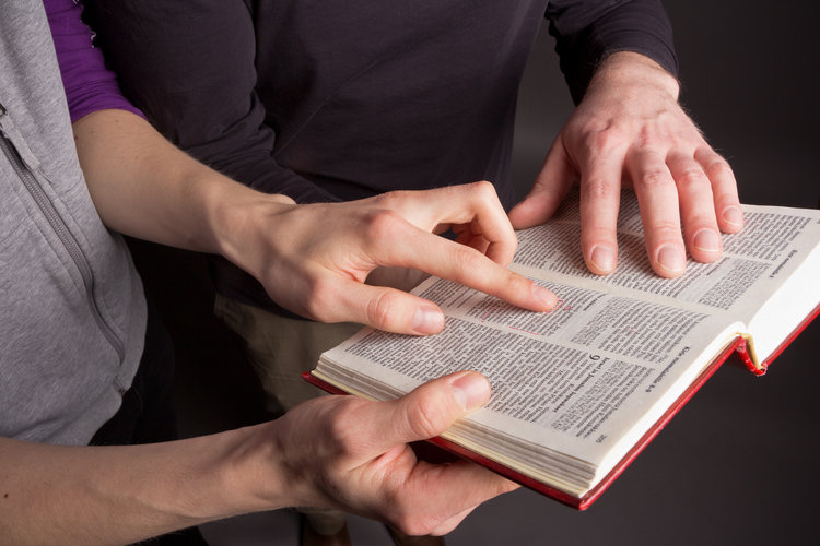 kahdet kädet pitävät kiinni raamatusta