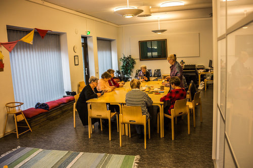 Hovinsaaren toimitila Pitkän pöydän ympärillä istuu naisia. Hovinsaaren toimitilan sisätilat.