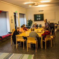 Hovinsaaren toimitila Pitkän pöydän ympärillä istuu naisia. Hovinsaaren toimitilan sisätilat.