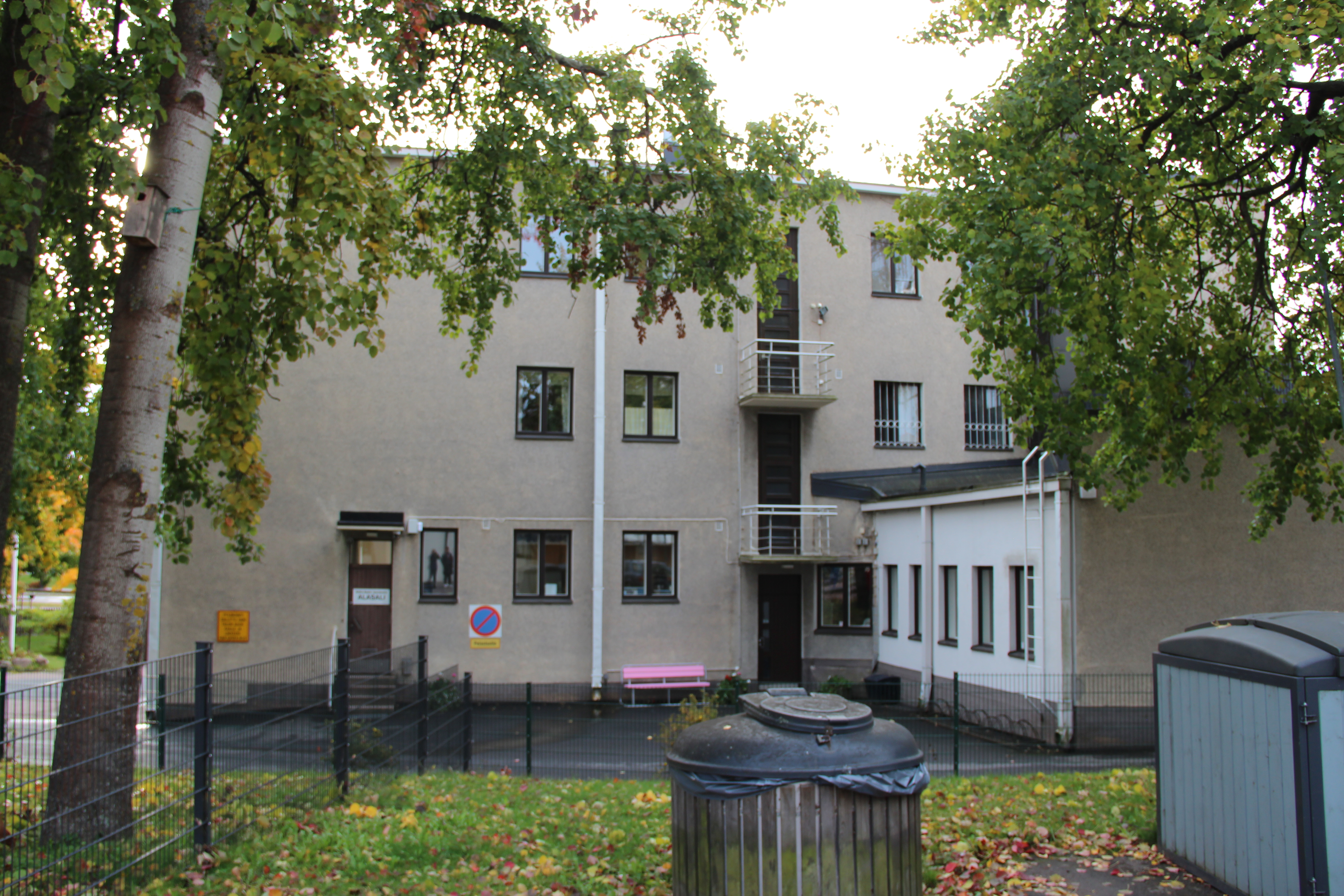 Alasali, Karhula Kolmekerroksinen, ruskeanharmaa kivitalo. Edessä aitaa, puita ja jäteastioita.
