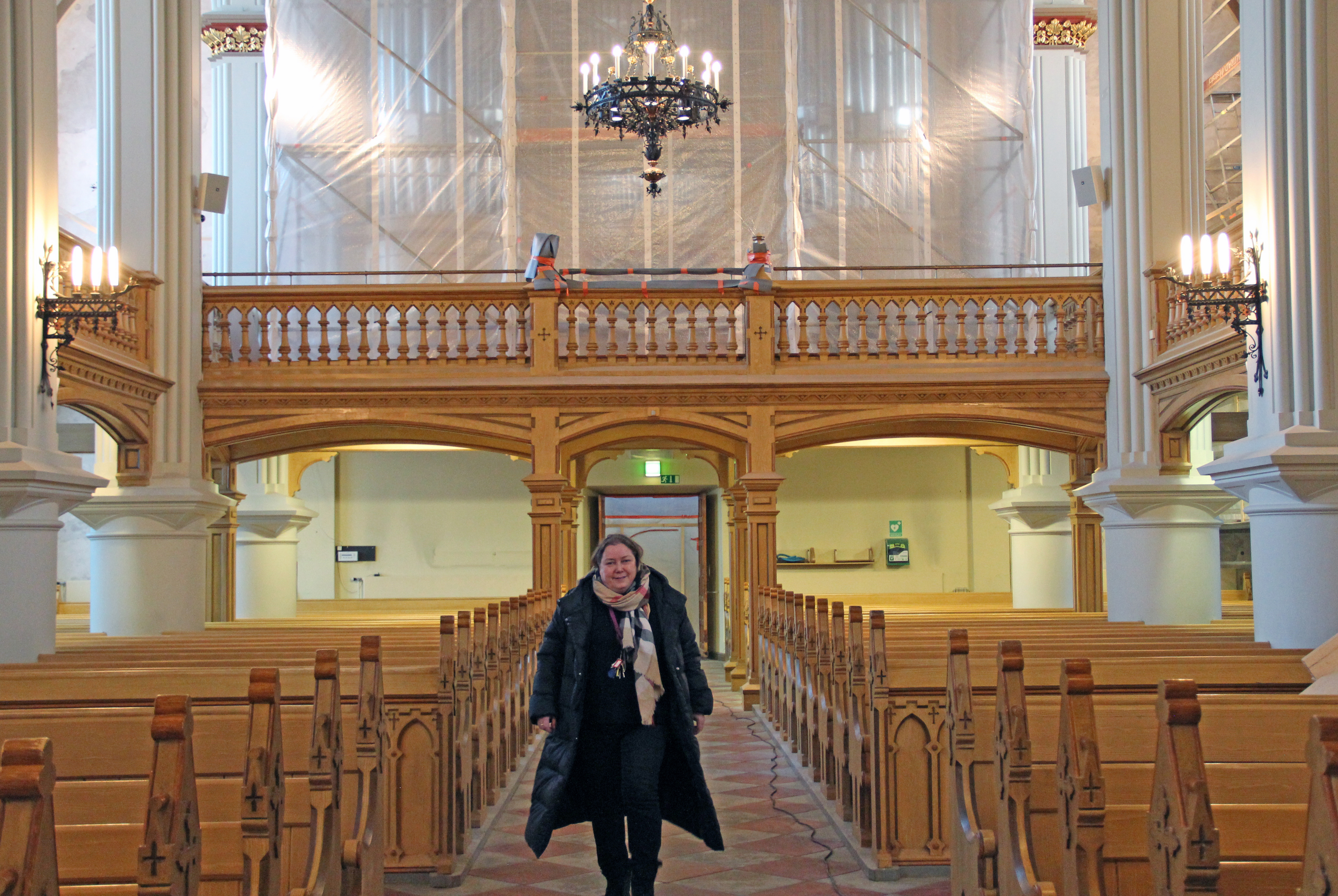 Liisa Sunila kävelee Kotkan kirkon käytävällä.